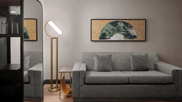 Una sala de estar moderna con un sofá gris, una lámpara de pie y obras de arte enmarcadas en la pared.