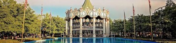 Un carrusel con decoraciones elaboradas y una piscina al frente.