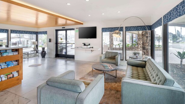 Un vestíbulo moderno con mostrador de recepción, zona de estar y ventanas amplias con vistas al exterior.