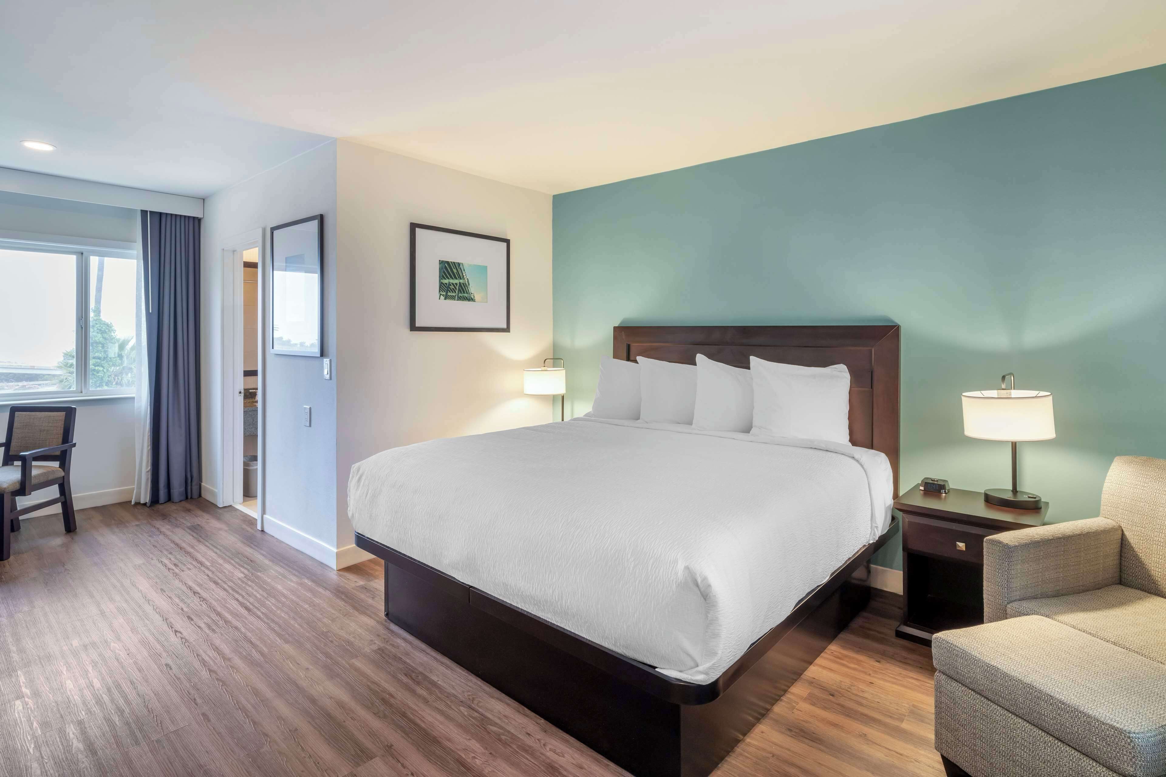 Habitación de hotel con una cama grande, un escritorio, una silla y vistas al exterior.