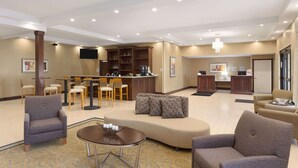 Un vestíbul d'hotel amb taulell de recepció, zona de seients i bar.