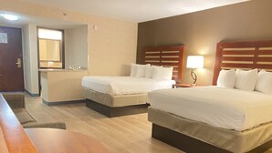 Habitación de hotel con dos camas, un escritorio, un espejo y una lámpara.