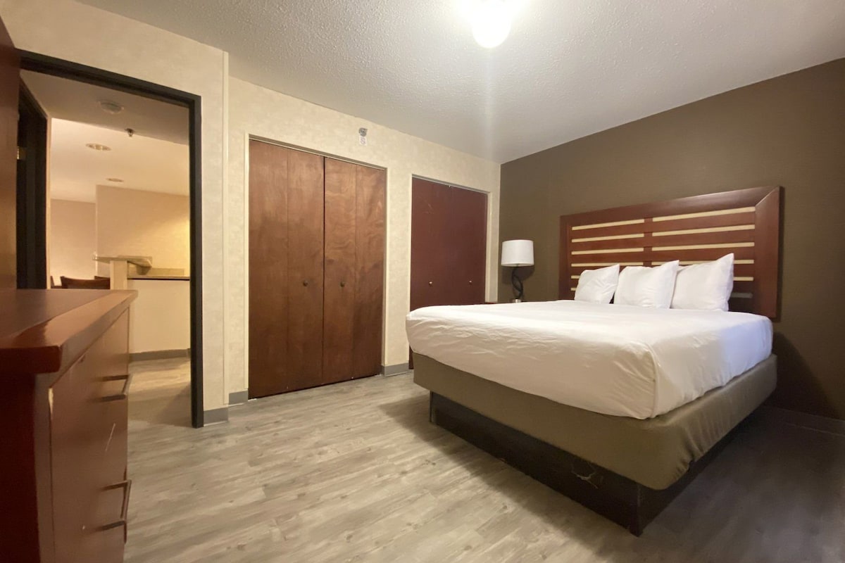 A hotel room with a bed, a dresser, and a wardrobe.