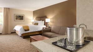 Habitació d'hotel amb un llit, un sofà, una cafetera i una bandeja amb vasos.