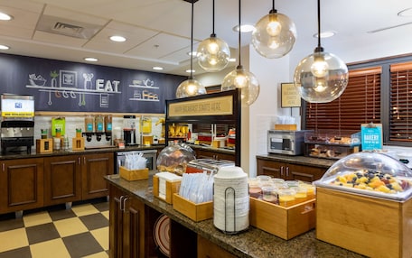A breakfast buffet area with various food items and a sign that reads "HAPPY BREAKFAST STARTS HERE".