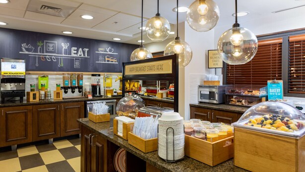 A breakfast buffet area with various food items and a sign that reads "HAPPY BREAKFAST STARTS HERE".