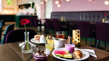 A dining table with breakfast items, including a croissant, a glass of juice, and a plate with a sandwich.