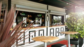 A bar area with a counter displaying bottles and glasses, surrounded by seating and potted plants. - Elite Grand Hotel Norrköping (Norrköping)