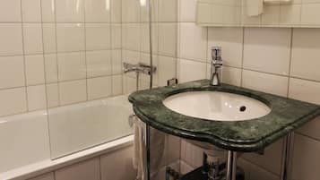 Un baño moderno con una bañera, un lavabo con encimera verde y un espejo sobre el lavabo.