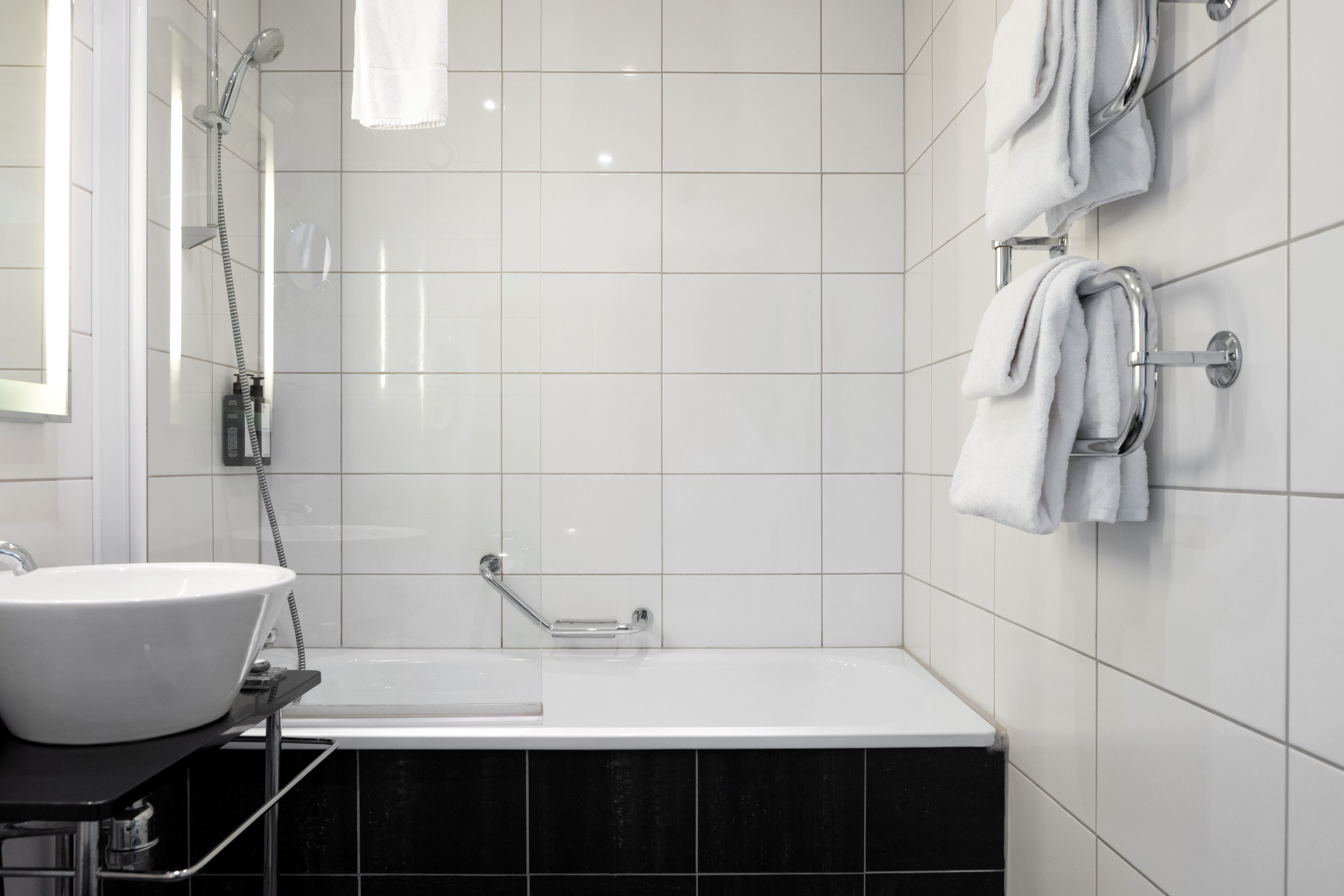 Ett modernt badrum med ett vitt handfat, ett badkar och en dusch.
