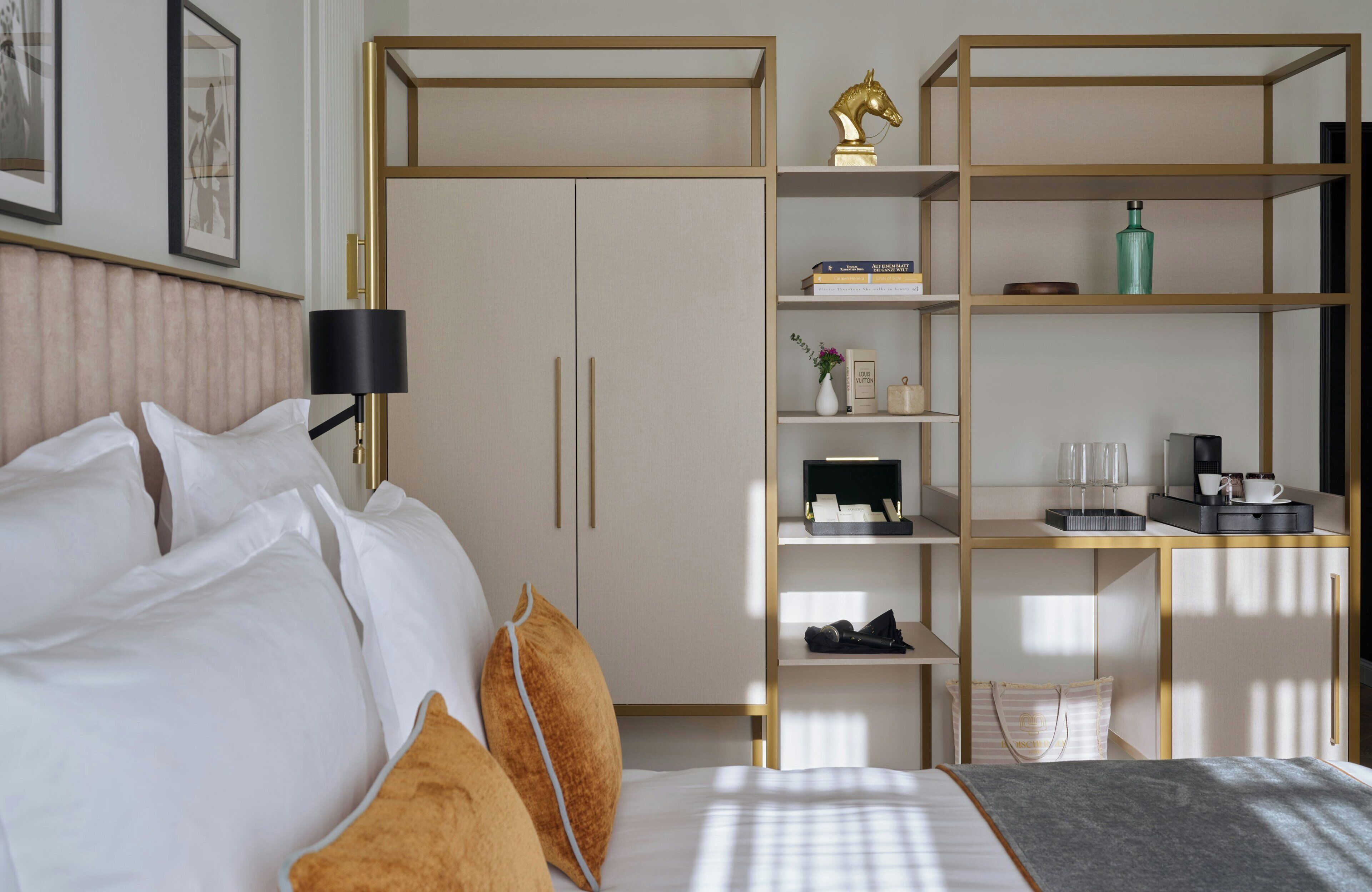 A hotel room with a bed, a wardrobe, a desk, and a lamp.