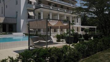 A poolside area with a sun lounger and a covered seating area.