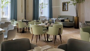 Un comedor moderno con mesas redondas, sillas tapizadas en verde y un sofá.