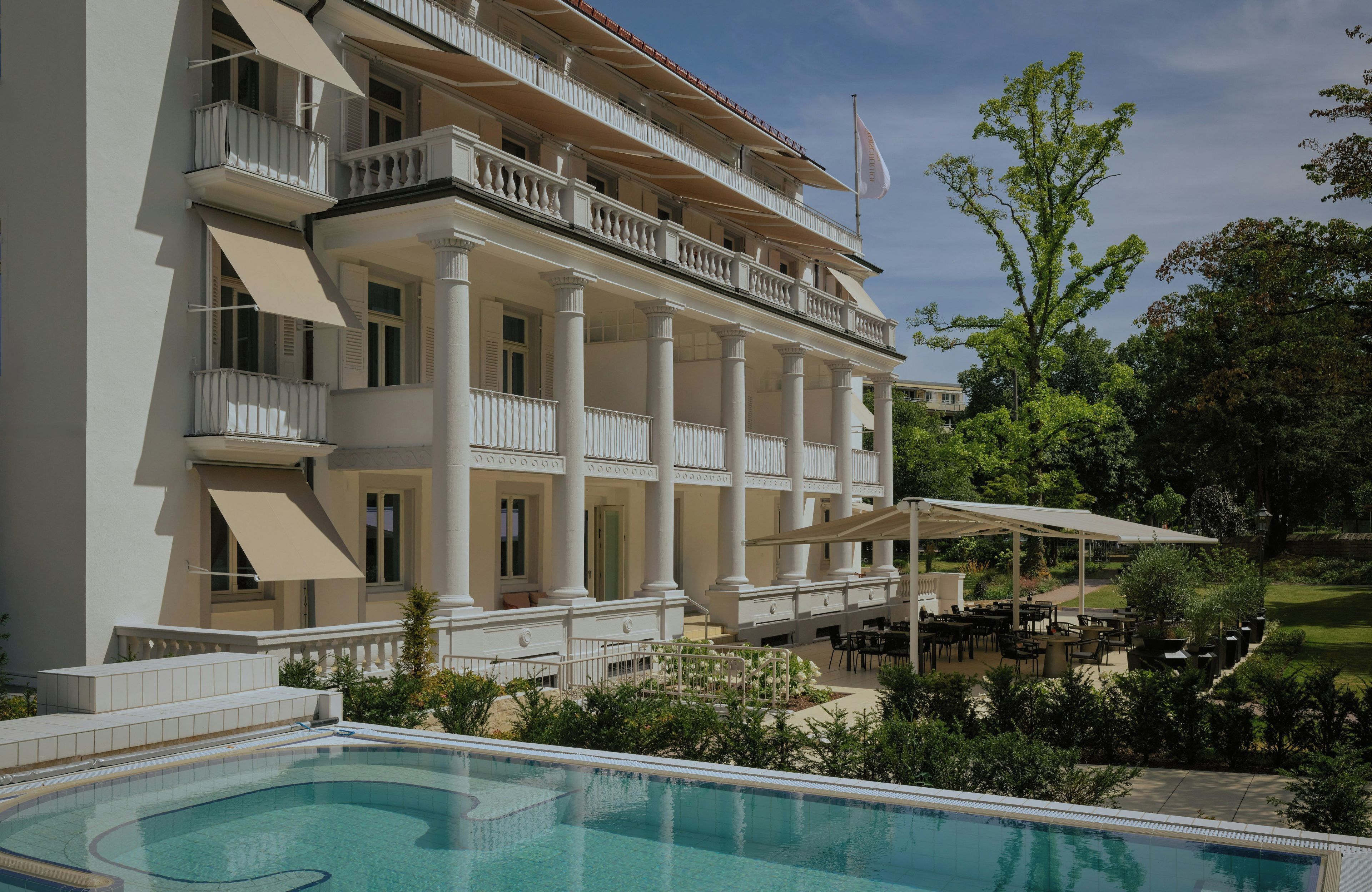 Ein Hotel mit Schwimmbad, Sitzgelegenheiten im Freien und einem Garten.