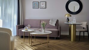 Una sala moderna con un sofá, dos mesas redondas, una silla y un espejo redondo en la pared.
