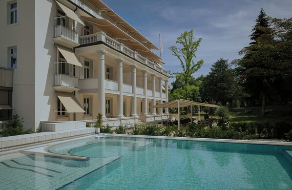 Un hotel con piscina, mobiliario exterior y jardín.