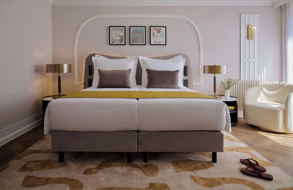 Una cama doble con cabecera, dos mesitas de noche, una silla y una lámpara de pie.