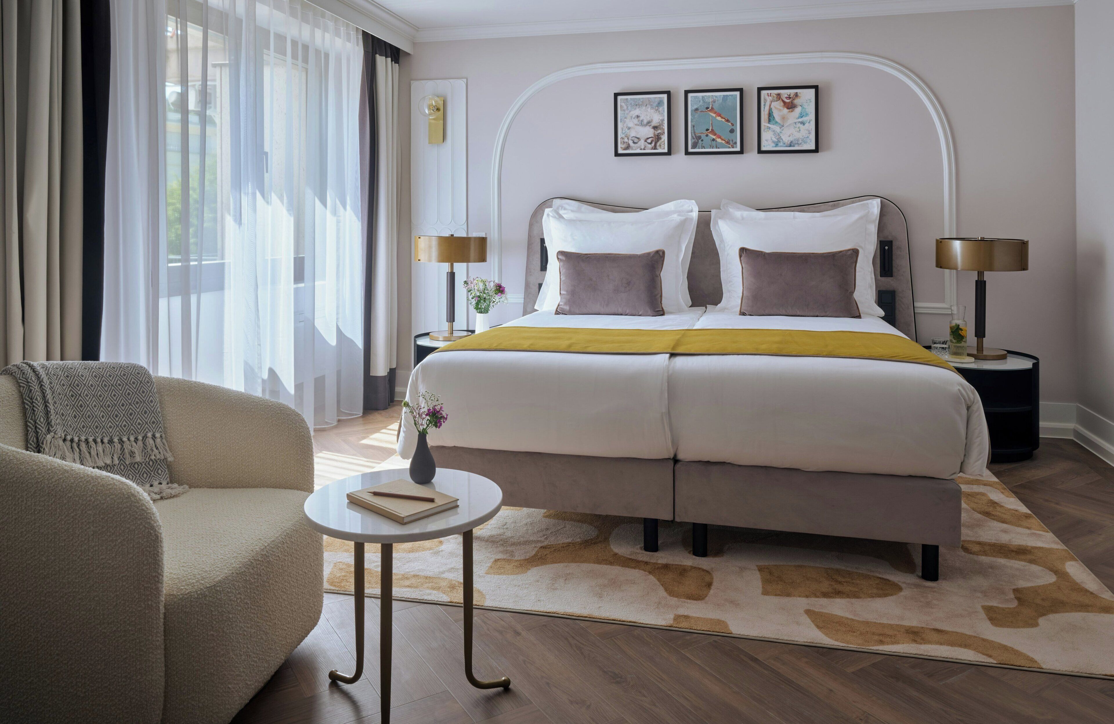 Ein Hotelzimmer mit Bett, Sofa, kleinem Tisch und Nachttisch mit Lampen.