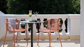 A balcony with two wicker chairs, a round table, and a vase with flowers. - Badischer Hof Baden-Baden - Leonardo Limited Edition (Baden-Baden)