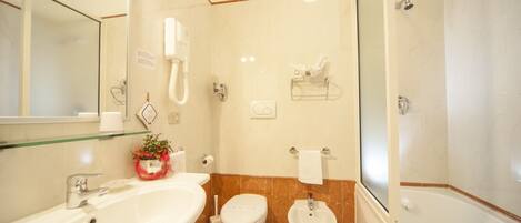 A bathroom with a large sink, toilet, bidet, and bathtub.