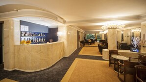 Un vestíbulo de hotel con mostrador de recepción de mármol, zona de estar y un bar.