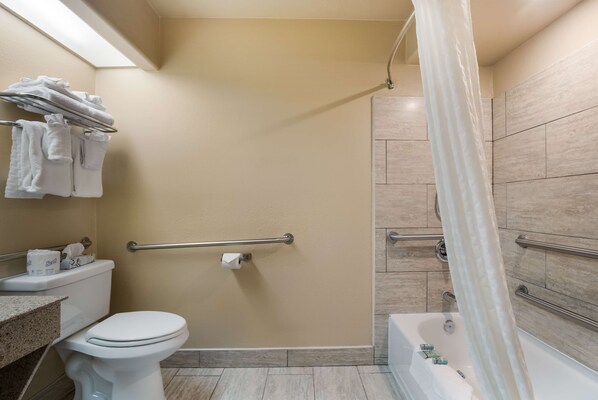 Un baño con inodoro, ducha con puerta de vidrio y bañera.