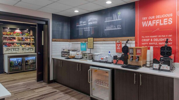Un comptoir de boulangerie équipé d’un appareil à gaufres, d’une vitrine réfrigérée et d’une enseigne publicitaire pour les gaufres.