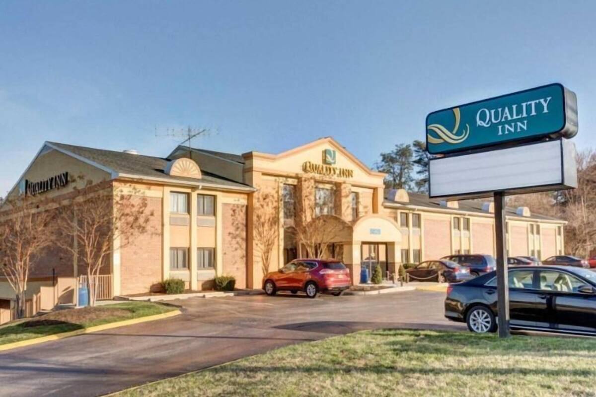 Quality Inn -hotelli, jossa on tiiliverhous, keskeinen sisäänkäynti ja pysäköintialue, jossa on autoja.