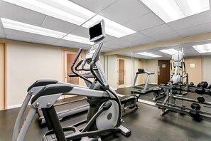 A gym with treadmills, elliptical machines, and a weight rack.