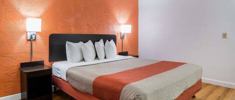 A neatly made bed with a red and white bedspread, two bedside lamps, and a small nightstand.