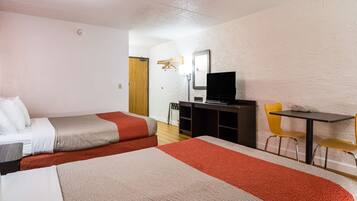 A hotel room with two beds, a desk, a chair, a television, and a mirror.