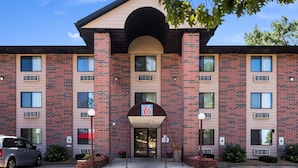 A multi-story brick building with a central entrance, numbered 6, and air conditioning units on the facade.