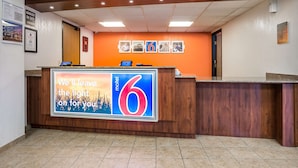 A hotel reception desk with a large sign reading "We'll leave the light on for you" and the number 6.