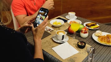 A breakfast setting with a variety of food items, including croissants, fruit, and a cup of coffee.