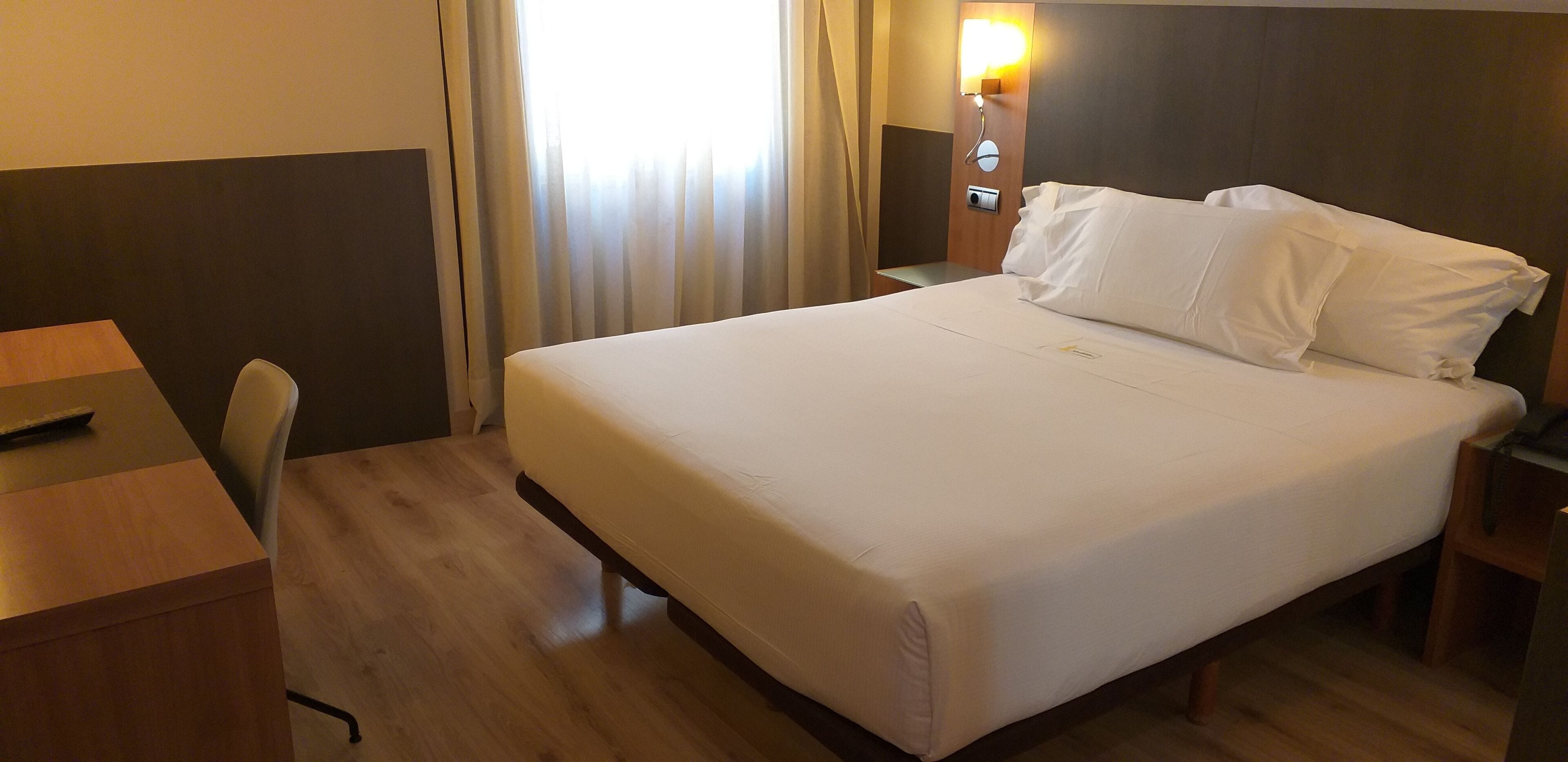 Una habitación de hotel con una cama grande, un escritorio y una silla.
