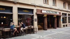 Un caffè con tavoli all'aperto e l'ingresso di un hotel.