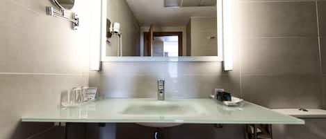 Un baño moderno con un lavabo de vidrio, un espejo y un perchero para toallas.