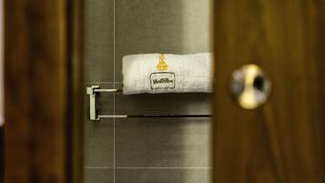 A bathroom with a towel hanging on a rack, a wooden door, and a tiled wall.