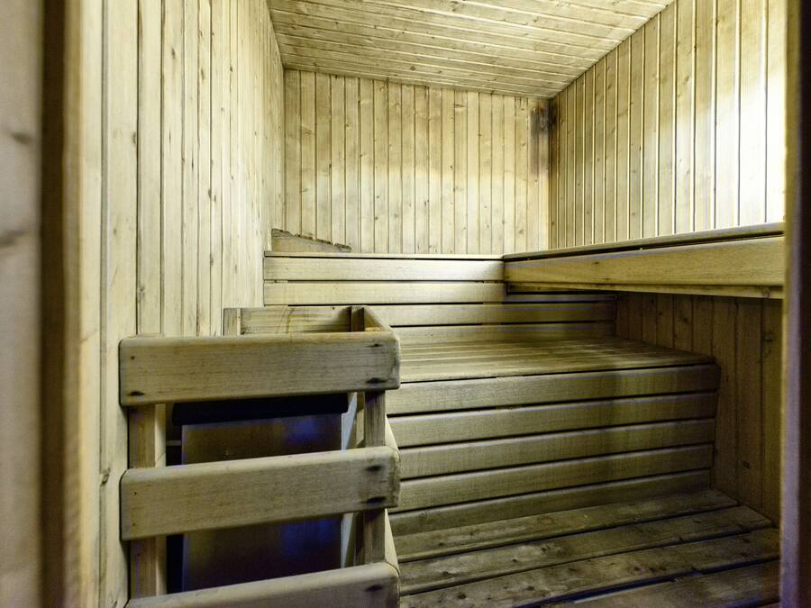 A wooden sauna with benches and a sloped ceiling.