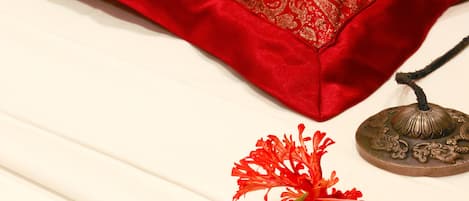 Una cama con un almohadón rojo y un objeto metálico decorativo encima.