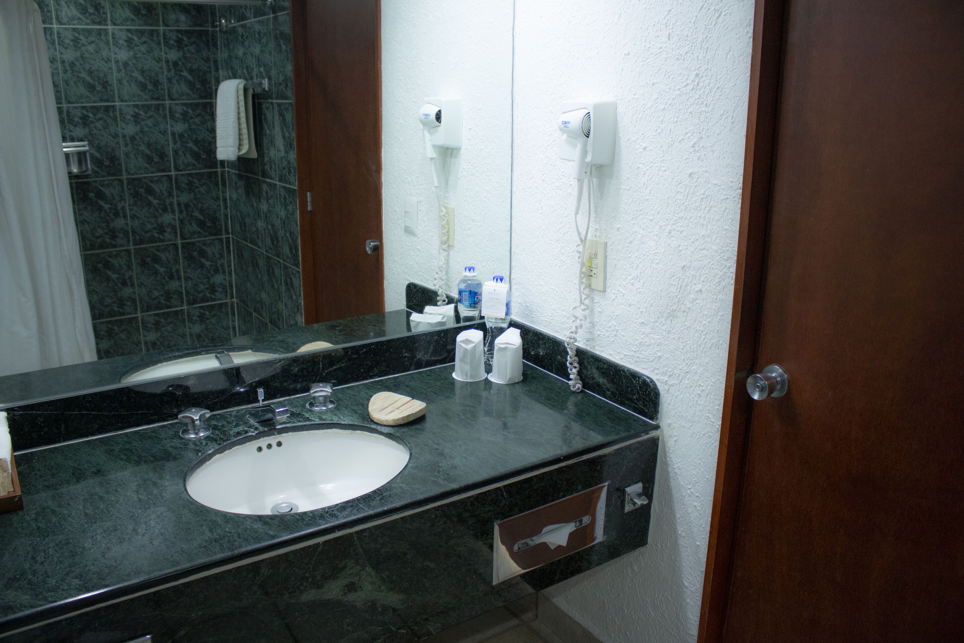 Un baño con lavabo, espejo, toallero y secador de pelo.