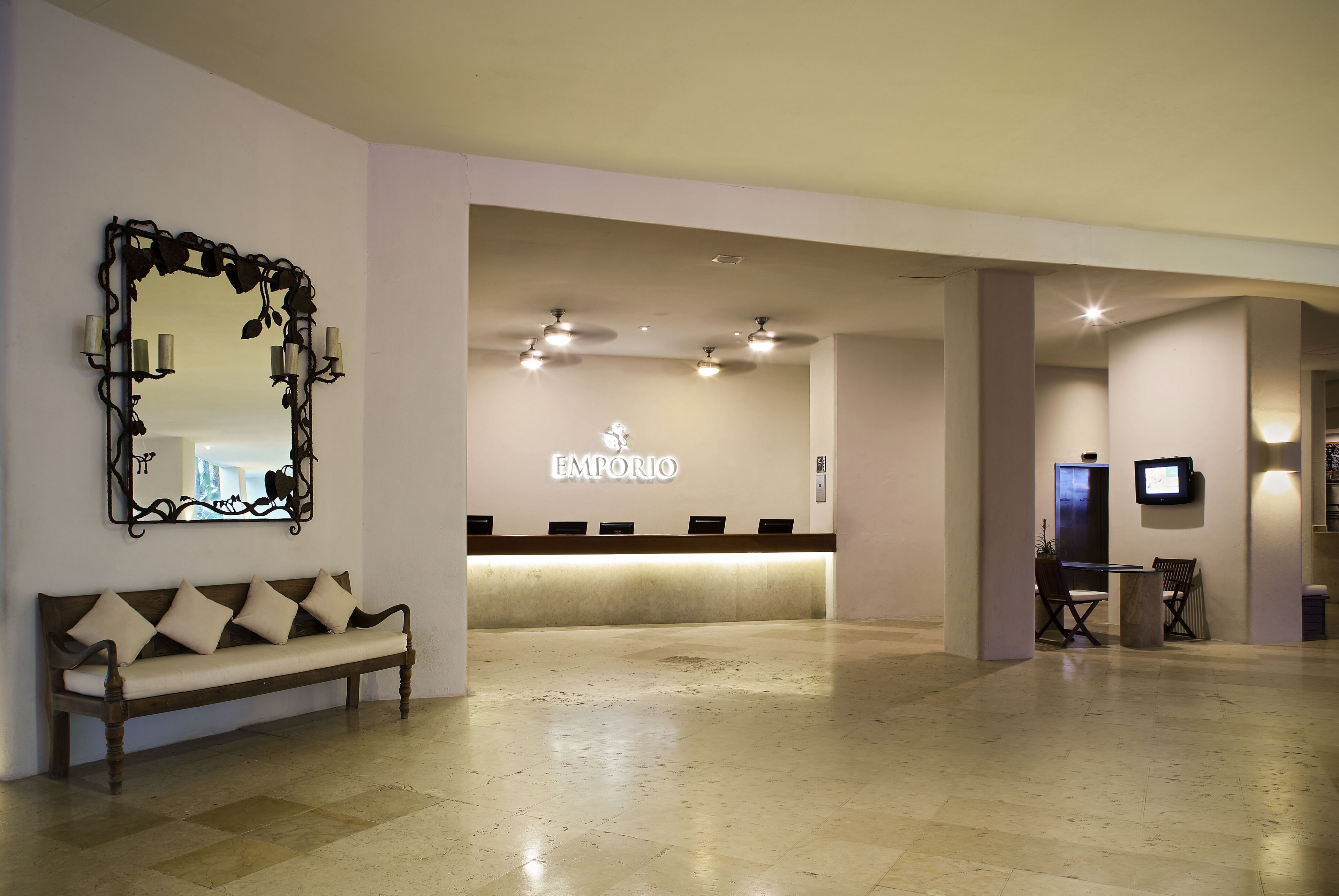 A reception area with a bench, a reception desk, and a large mirror.