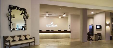 A reception area with a bench, a reception desk, and a large mirror.