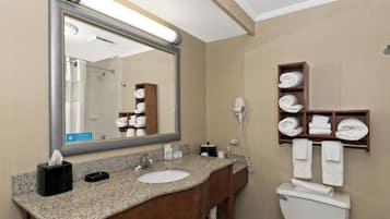 A hotel bathroom with a sink, mirror, towel rack, and toilet.