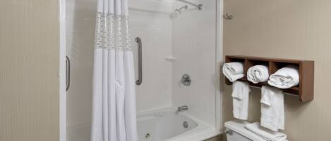 A bathroom with a shower, bathtub, toilet, and a towel rack with neatly folded towels.