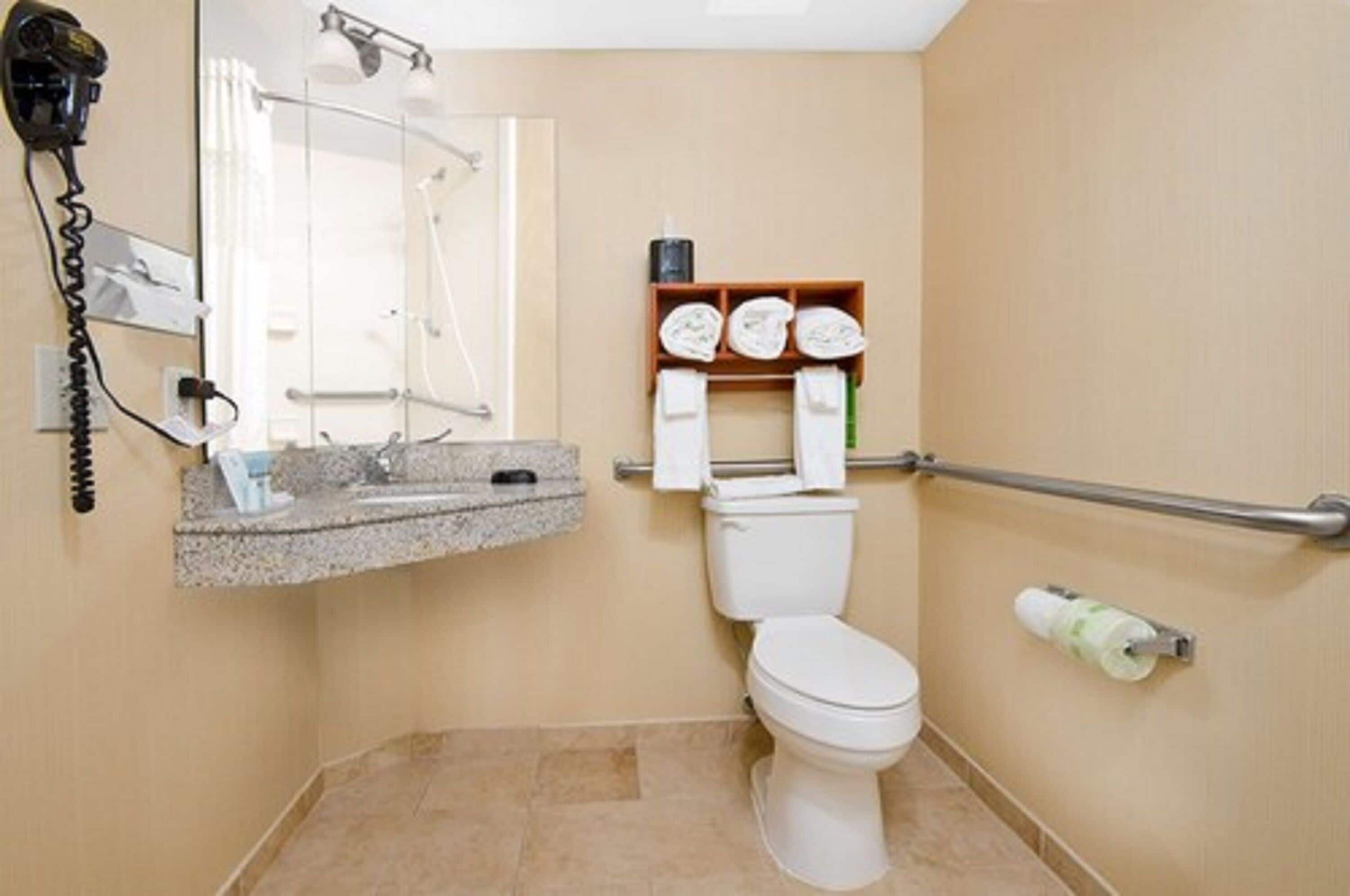A bathroom with a toilet, a sink with a towel rack, and a hairdryer on the wall.