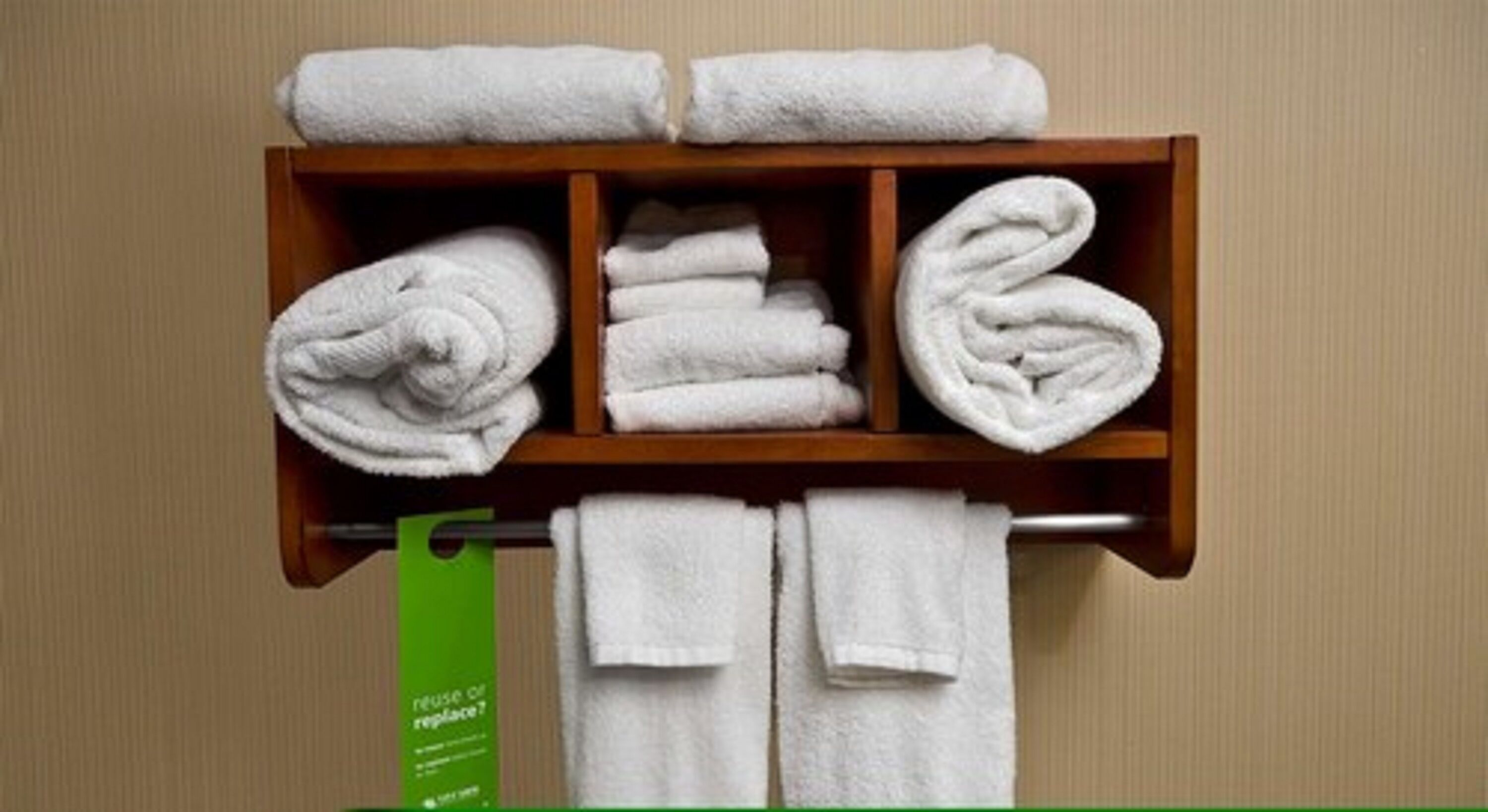 A wooden towel rack with neatly folded white towels.