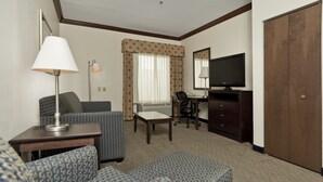 Une chambre d’hôtel équipée d’un canapé, d’un fauteuil, d’un bureau, d’une télévision et d’une armoire.