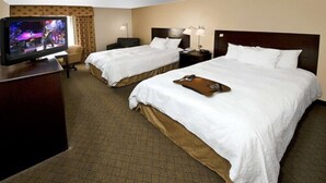 A hotel room with two beds, a TV, a desk, and a chair.