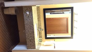 A bathroom with a granite countertop, a wooden door, and a mirror.
